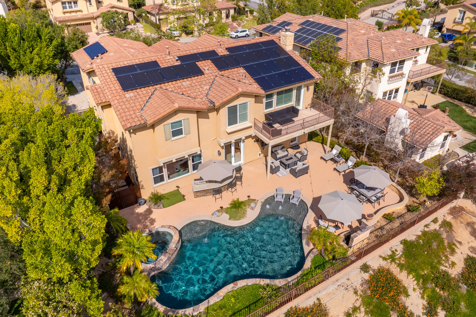 Aerial view of solar panels, pool, and backyard entertaining